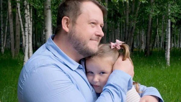 Papà sorridente abbraccia dolcemente la sua figlioletta, 3 anni, godendo della paternità. Festa dei padri. Buon concetto di infanzia e genitorialità. Protezione dei minori — Foto Stock