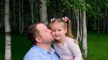 Baba 3 yaşındaki küçük kızını nazikçe yanağından öpüyor. Babalar Günü. Mutlu çocukluk kavramı..