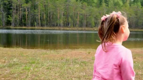 분홍색 스웨트 셔츠를 입고 두 머리가 달린 3 세 소녀가 자연스럽게 밖에서 놀고 있는 모습. 행복 한 어린 시절의 개념, 아이들의 발달 — 비디오