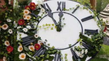 Sahada çiçek açan büyük duvar saati, saati 11: 55, 12: 00 gösteriyor. Zaman yönetimi kavramı, gün ışığı tasarrufu. Bahar ya da düğün. Kadınlar için piknik günü