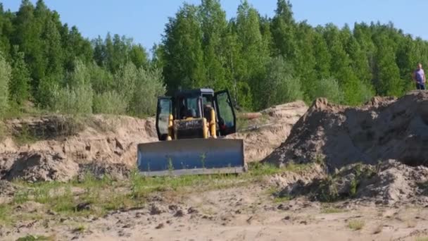 Gelber Traktor führt Erdarbeiten aus, um Sand auf einer Baustelle auszuheben: Moskau, Russland - 30. August 2021 — Stockvideo