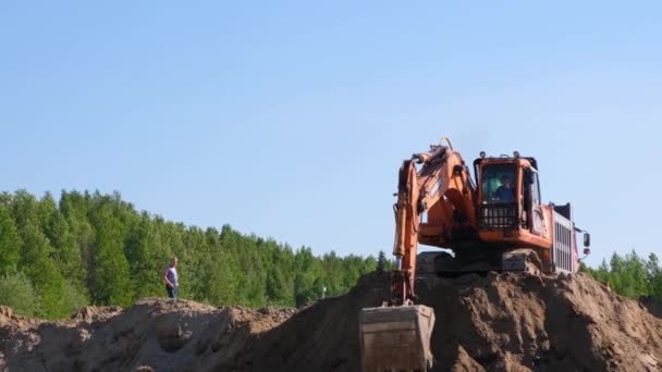 Gele graafmachine bulldozer voert grondwerken uit door zand te graven op een bouwplaats: Moskou, Rusland - 30 augustus 2021. — Stockvideo