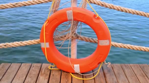 Cordones anaranjados de salvamento y mar en el fondo del mar y el cielo azul. Cuerdas marinas y salvavidas colgando de un poste. Ayuda y concepto de seguridad — Vídeo de stock