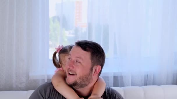 Skrattar Lilla dotter 3 år gammal och far försiktigt krama och ha kul hemma. Ha kul med ditt barn, dumskalle. Pappadagen. föräldraskap, relationer mellan barn och föräldrar — Stockvideo