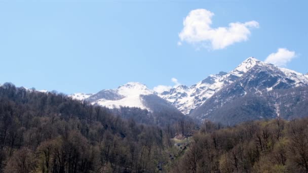 Bela paisagem de montanhas cobertas de neve com nuvens brancas no céu azul em um dia ensolarado em Krasnaya Polyana em Sochi, Rússia. Famosa estância de esqui — Vídeo de Stock