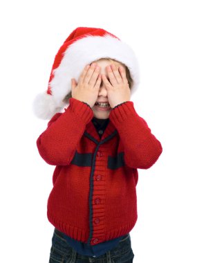 Noel Baba şapkalı bir çocuk elleriyle yüzünü kapattı, saklambaç oynuyordu..