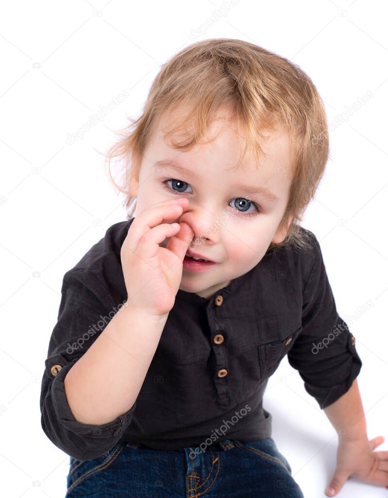 Funny baby toddler blonde boy picking his nose isolated on white background