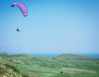 Dağlar ve deniz üzerinde uçan Yamaçparaşütü