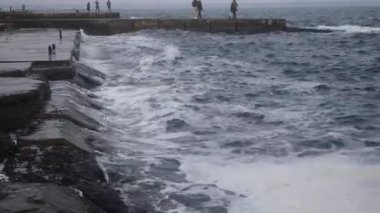 Deniz dalgaları sahilin kayalık sahillerine vuruyor.