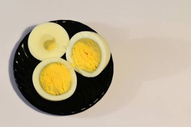 Haşlanmış, soyulmuş ve kesilmiş bir tavuk yumurtası seramik tabakta beyaz bir masada yatıyor. Yüksek kalite fotoğraf