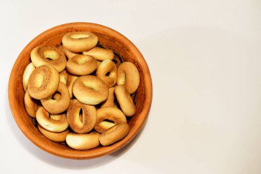 Çörekler seramik bir tabağa konmuş ve beyaz bir masaya konmuş.