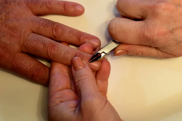 Men\'s hands on which the master cuts off the old skin from the fingers with a tool. High quality photo