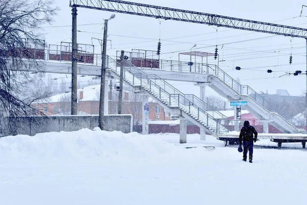 Um homem caminha pelas nevascas até a ponte ferroviária. — Fotografia de Stock