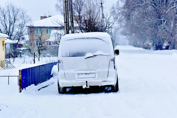 Na zaśnieżonej ulicy jest samochód pokryty śniegiem. — Zdjęcie stockowe