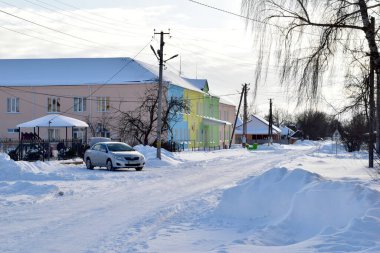 Resim köy okulunun binasını ve yakınındaki karla kaplı yolu gösteriyor. Yüksek kalite fotoğraf