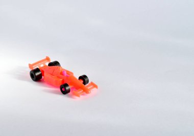 Siyah tekerlekleri açık kırmızı yarış arabası. Plastikten yapılmış.