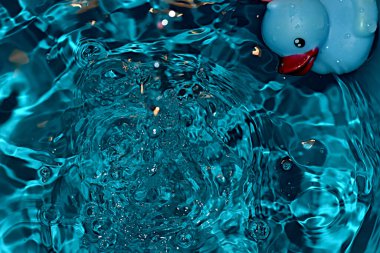 Düşen damlacıklar suyun üzerinde dokulu bir hava kabarcığı deseni yarattılar..