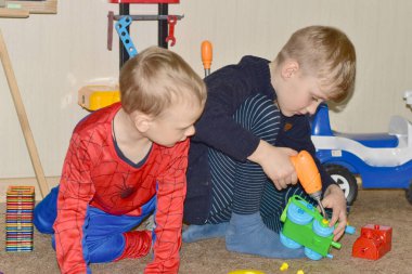 Evde oynayan çocuklar oyuncak bir araba monte ediyorlar..