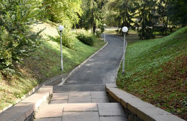 Fenerlerle donatılmış bir taş park merdiveni ve bir patika..