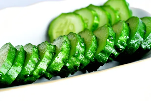 Egy közeli kép egy szeletelt zöld uborkáról egy tányéron.. — Stock Fotó
