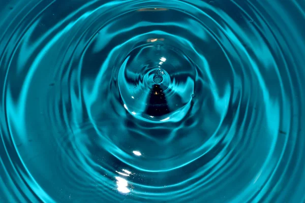 Amplias, incluso círculos de agua en la superficie del líquido de las gotas que caen. — Foto de Stock