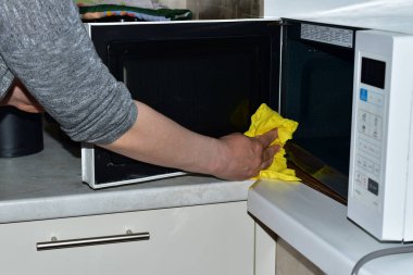 Kadın mikrodalga fırını peçeteyle siler..