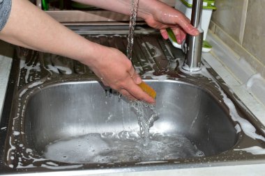 Bir kadın ellerini akan suyun altında yıkar..