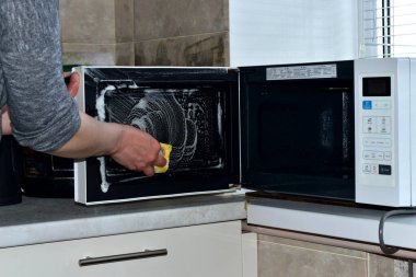 Bir kadın mikrodalgayı havluyla yıkıyor..