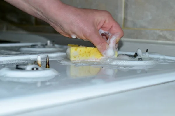 Close-up de uma mão feminina lavando a superfície de um fogão a gás com uma esponja. — Fotografia de Stock