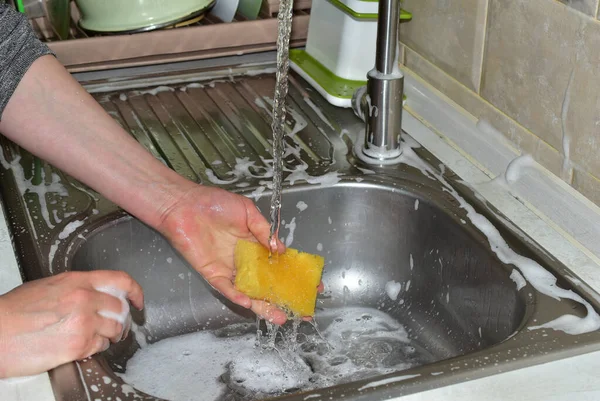 Eine Frau wäscht ein Waschlappen unter fließendem Wasser. — Stockfoto