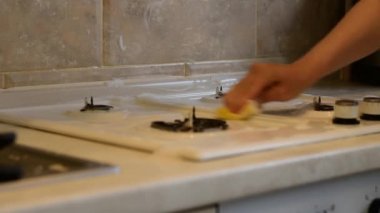Kadın gaz sobasının yüzeyini ocağın yanındaki peçeteyle siliyor..