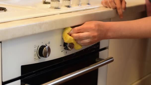 オーブンをオンにするハンドルの近くに表面を拭くためにナプキンを持つ女性 — ストック動画