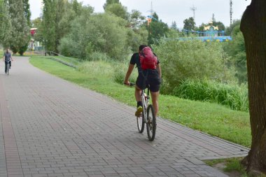 Sporcu parkta bisiklet sürüyor..