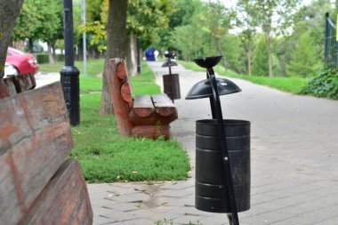 Çöp tenekesi parktaki bankların arasında..