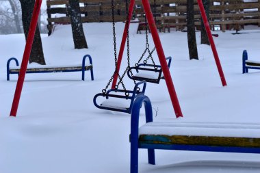 Çocukların üzerinde kar var, metal zincirlerle salınıyorlar..