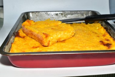 Süzme peynir ve balkabağından yapılmış bir güveç kahverengi bir kabın içinde oturur. Yan görünüm.