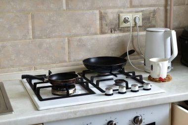 Gaz sobasının yüzeyinde kızartma tavaları var..