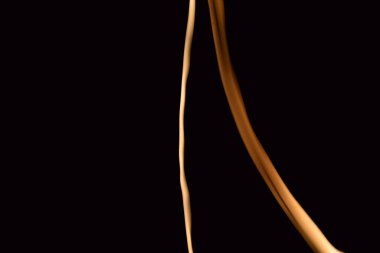 Siyah bir arkaplanda yanan bir mumun rastgele hareketi tarafından oluşturulan soyut bir figürün arkaplan resmi.