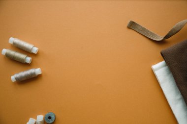 Mavi arka planda aksesuar ve kumaş dikmek. Kumaş, dikiş iplikleri, iğne ve dikiş santimetresi. Üst görünüm, düz görünüm, kopyalama alanı