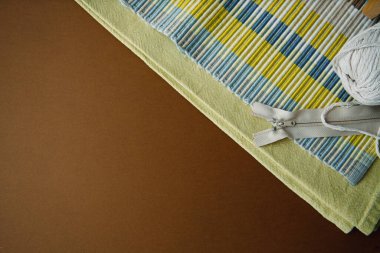 Mavi arka planda aksesuar ve kumaş dikmek. Kumaş, dikiş iplikleri, iğne ve dikiş santimetresi. Üst görünüm, düz görünüm, kopyalama alanı