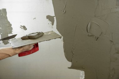 Bir işçi duvarı spatulayla kaplıyor ve çimento karışımı solüsyonu uyguluyor. Tamirci alçıpanı alçıpan üzerine serer. Tamirci evi tamir ediyor. İşçi konutları restore ediyor. Uzman çatlakları kapatıyor.