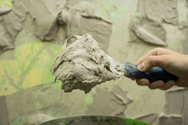 Bir işçi çimento karışımına bir çözüm bulmak için spatula kullanır. Usta sıva koyar. Tamirci evi onarır. Bir işçi evini restore eder. Tamirci evde tamirat yapar.