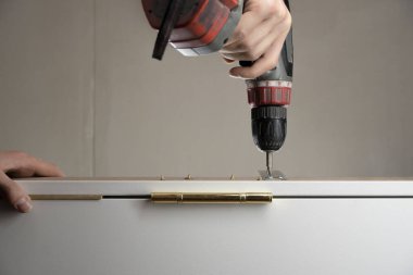 Bir işçi matkapla tahtaya vida sokuyor. Tamirci ev işi yapar ve konutu geliştirir.