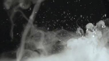 Sulu su damlaları ve sisli videoları rahatlatıyor ya da siyah bir arkaplanda döngü yapabilen dumanlar. Su yakın planda sıçrar. Su damlar ve hareket halinde zıplar. Kimyasal reaksiyon suyu.