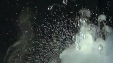 Sulu su damlaları ve sisli videoları rahatlatıyor ya da siyah bir arkaplanda döngü yapabilen dumanlar. Su yakın planda sıçrar. Su damlar ve hareket halinde zıplar. Kimyasal reaksiyon suyu.