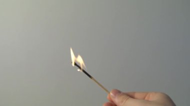Işıklı kibrit, gri arka planda dumanla yanar. Ateşli yavaş çekim videosu kavramı. El bir kibrit yakar.