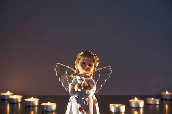 White Christmas angel with lighted candles in the Church. Spiritual deity in religion.
