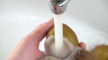 Kadın eli lavaboda ya da lavaboda kivi meyvesi yıkıyor..