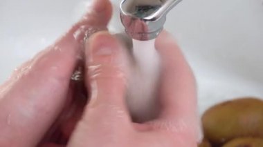 Kadın eli lavaboda ya da lavaboda kivi meyvesi yıkıyor..