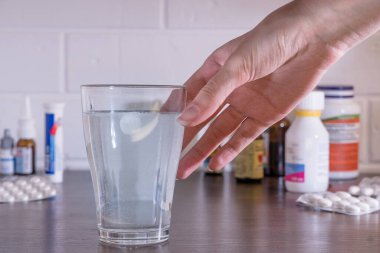 Ellerinizi tablet ve ilaçların arka planına dayayarak çözünen tabletlerle bir bardak su alın. Bardağa ilaç dolu su döküldü. Hapları suya at..